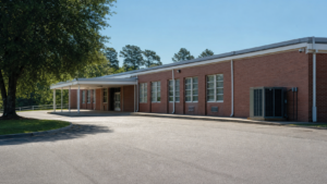 A quiet school building exterior on a hot summer morning, representing classroom cooling and ventilation planning.